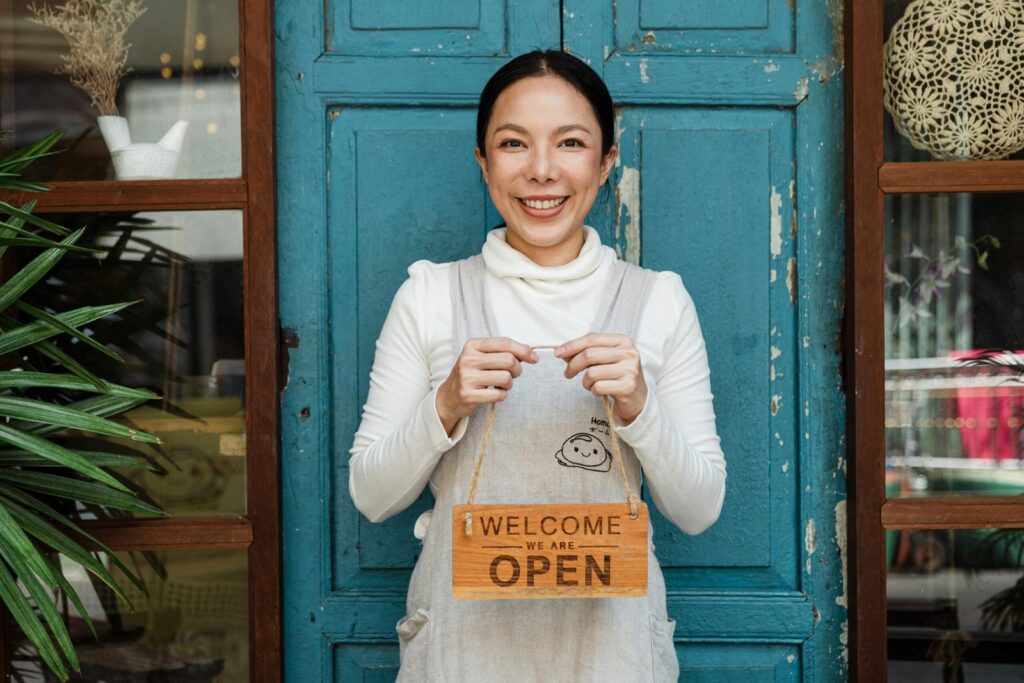 Happy small business owner holding open sign
